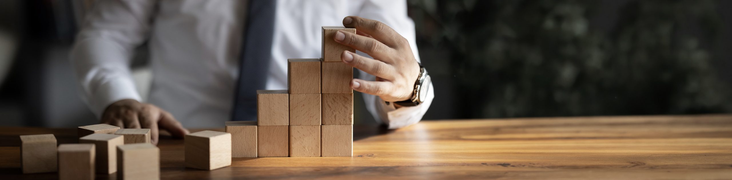 Ein Mann baut eine Treppe mit Holzbausteinen.